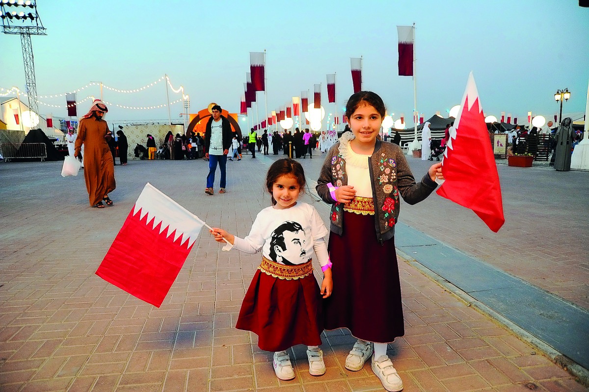 Kids with Qatar National flags at Darb Al Saai. 