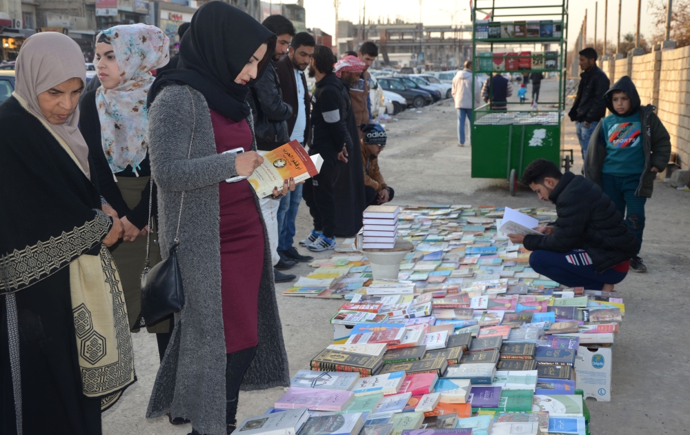 File photo of Iraqis buying and selling books on a pavement in the former embattled city of Mosul on January 12, 2018 six months after Iraqi forces retook the northern city from Islamic State (IS) jihadists. / AFP / Ahmad MUWAFAQ