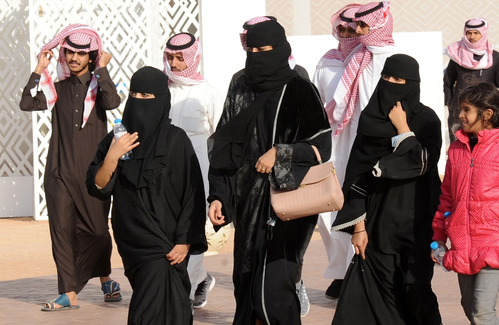 A picture taken on January 19, 2018 shows Saudi women and men walking during the King Abdulaziz Camel Festival in Rumah, some 160 kilometres east of Riyadh. AFP / FAYEZ NURELDINE