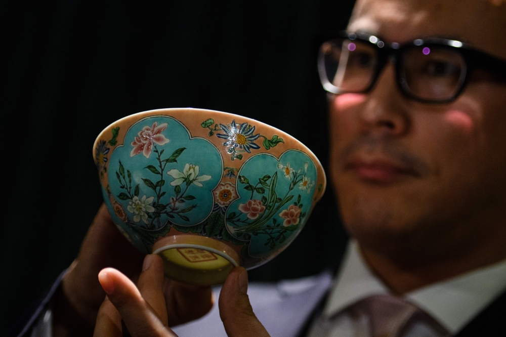 Nicolas Chow, deputy chairman for Sotheby's Asia, holds an extremely rare Qing Dynasty bowl -- one of only three known to exist -- during a media preview at auction house Sotheby's in Hong Kong on March 1, 2018, before its upcoming sale on April 3. AFP / 