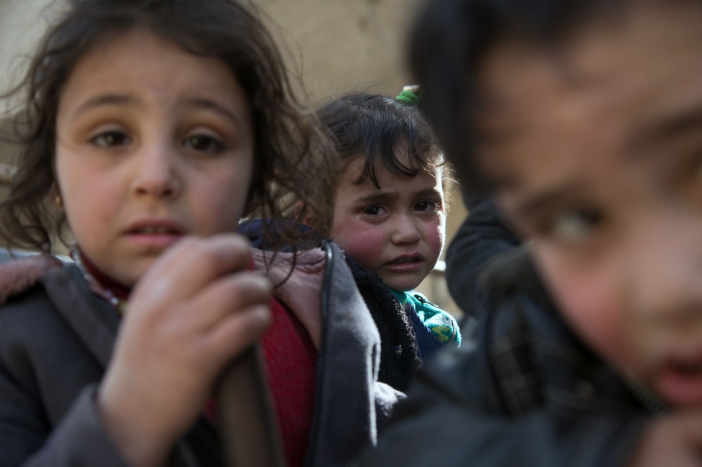 Syrian children sit in the back of a truck driven by White Helmets, as they flee their homes in the town of Beit Sawa in Syria's besieged eastern Ghouta region on March 4, 2018, following reported air strikes. AFP / Abdulmonam Eassa