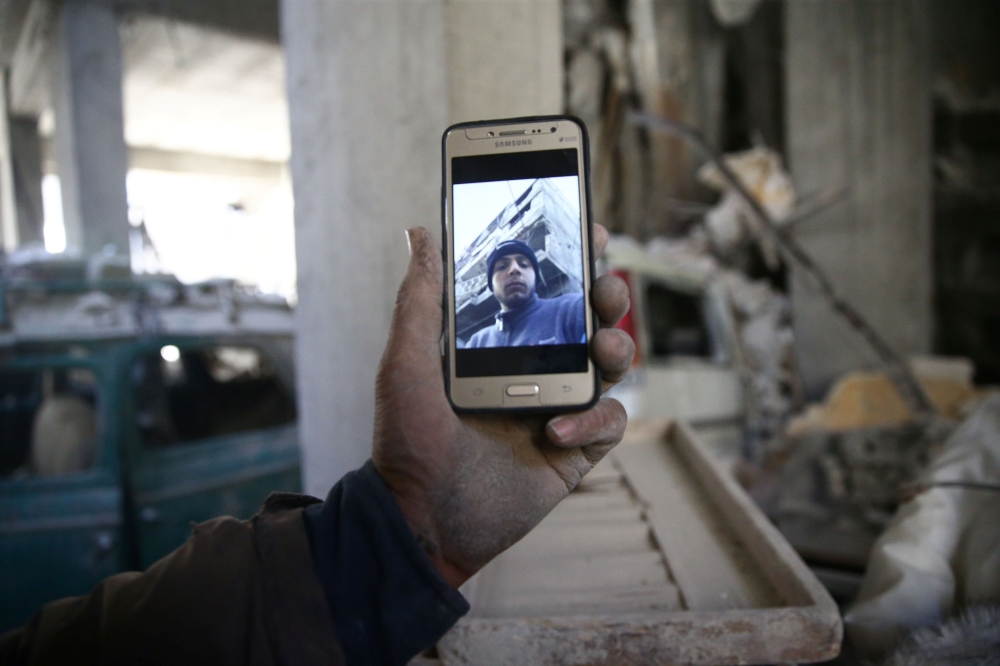 Abu Mohammad Alaya, 50, holds a mobile phone with his son Mohammad's picture on the screen, who was killed, in Douma, Syria March 2, 2018. Picture taken March 2, 2018. Reuters/Bassam Khabieh