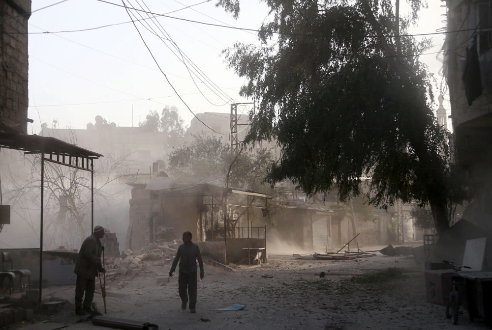 Syrians walk in the street covered in dust following reported government bombardments on the rebel-held town of Hamouria, in the besieged Eastern Ghouta region on the outskirts of the capital Damascus on March 5, 2018. / AFP / ABDULMONAM EASSA
