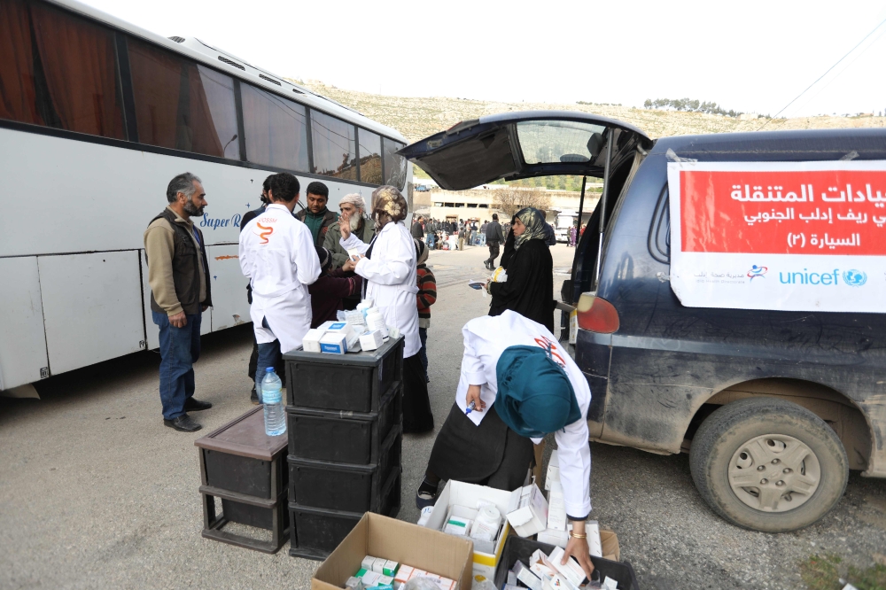 Aid workers wait for busses carrying rebel fighters and their families to arrive in the Qalaat al-Madiq village in the province of Hama, on March 13, 2018, after being evacuated from the Qadam neighbourhood on the outskirts of Damascus under a deal agreed