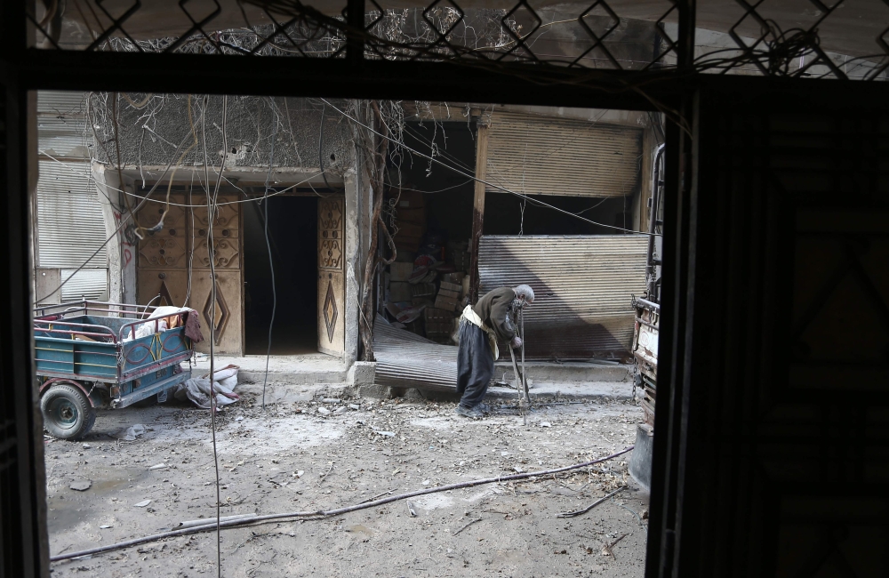 An elderly Syrian man looks for a safe place to take shelter in the rebel-held town of Hamouria in the Eastern Ghouta region on the outskirts of Damascus during bombardment by government forces on March 14, 2018. / AFP / ABDULMONAM EASSA
