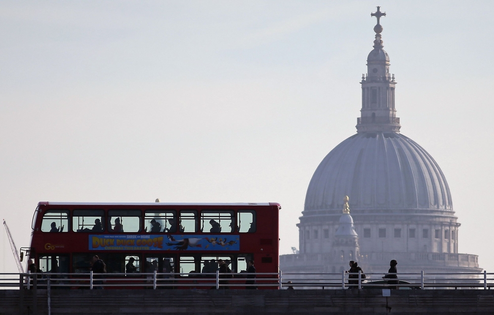 Commuters cross Waterloo Bridge in London bus and on foot as they cross the River Thames and make their way into the City of London, on March 21, 2018, backdropped by the dome of St Paul's Cathedral.  AFP / Daniel Leal-Olivas