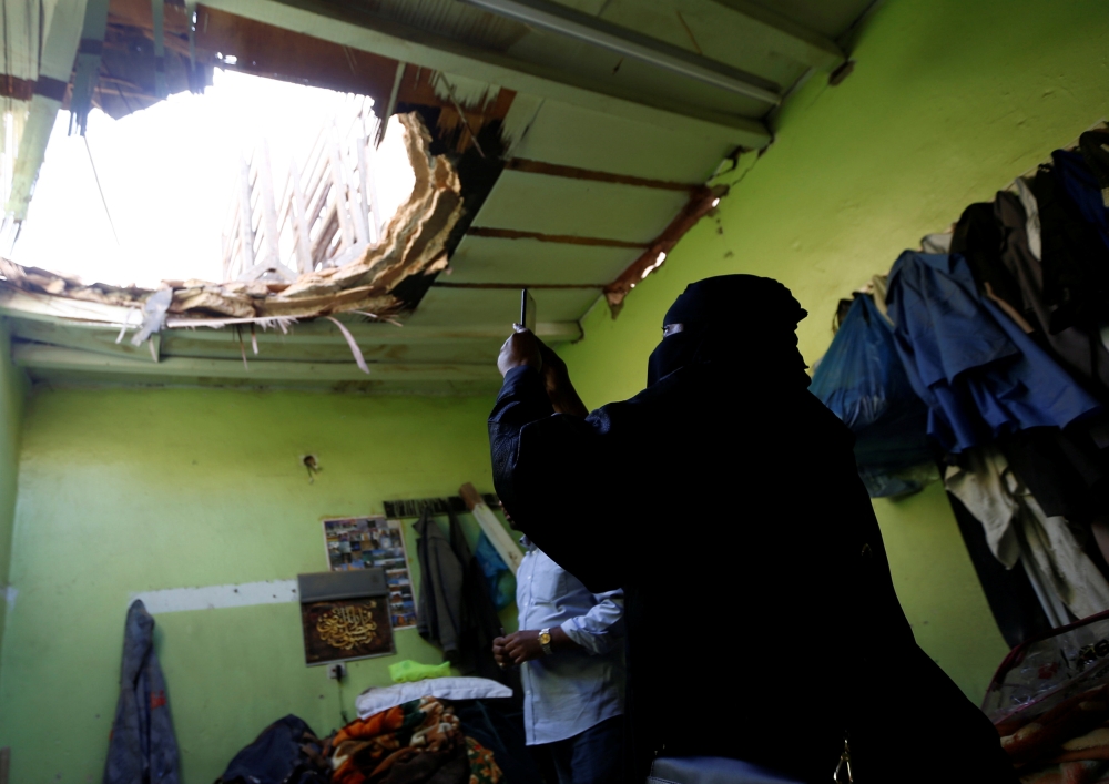 A woman uses her mobile phone to take picture of the damage created by debris, after ballistic missiles fired by Yemen's Houthi militia, fell at a house in Riyadh, Saudi Arabia March 26, 2018. REUTERS/Faisal Al Nasser