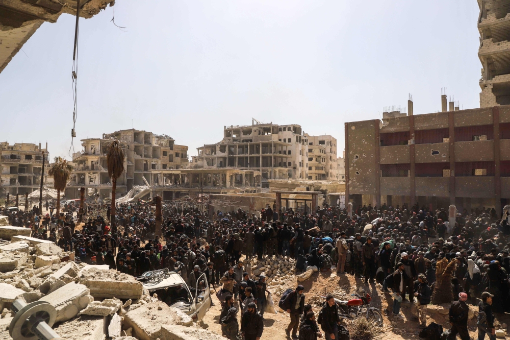 A picture taken on March 25, 2018 shows Syrian civilians gathering for their evacuation from the town of Arbin in the Eastern Ghouta region on the outskirts of the capital Damascus, following a deal with the regime. AFP / AMER ALMOHIBANY
