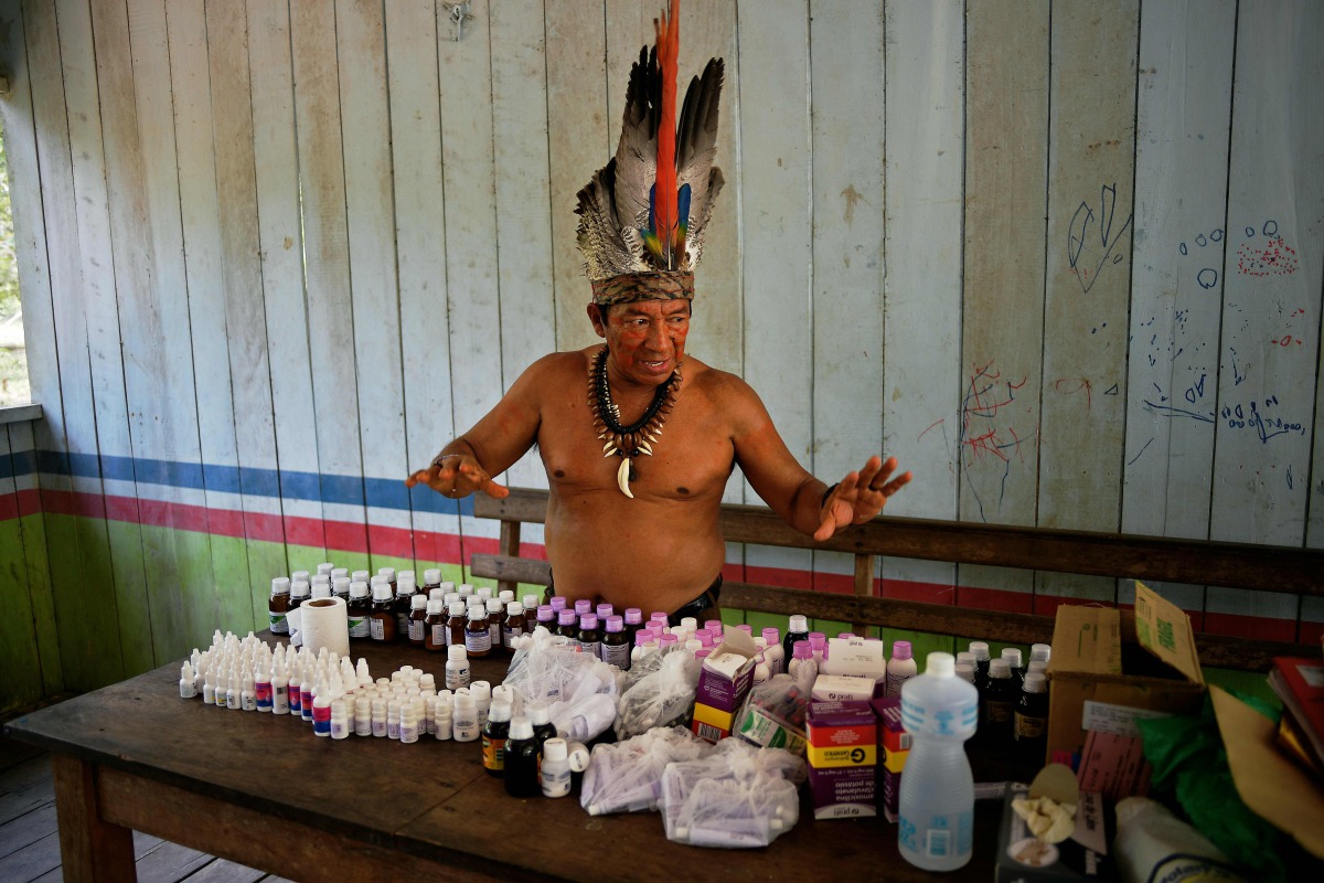 Chief Marcelino Apurina of the Aldeia Novo Paraiso in the Western Amazon region of Brazil near Labrea stands by a table of modern medicines delivered to the village on September 21, 2017. (AFP / Carl De Souza) 