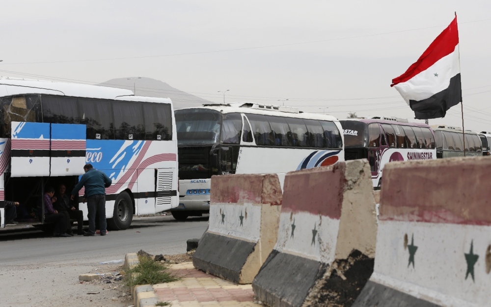 Syrian government buses gather to evacuate civilians and rebel fighters from the town of Douma on the government side of the Wafideen checkpoint on the outskirts of Damascus neighbouring the rebel-held Eastern Ghouta region, on April 3, 2018.   AFP / Loua