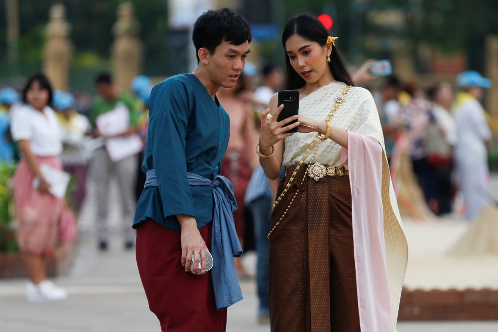 People dressed in traditional costumes look at a mobile phone at the Royal Plaza, as interest for historical clothing rises within the country, in Bangkok, Thailand April 6, 2018. Reuters/Soe Zeya Tun