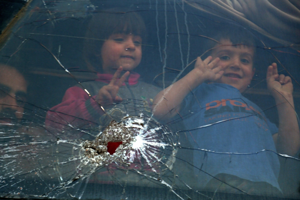 Children look out of the window of a bus upon their arrival at the Abu al-Zindeen checkpoint near the northern Syrian town of al-Bab after Jaish al-Islam fighters and their families from the former rebel bastion's main town of Douma were evacuated from th