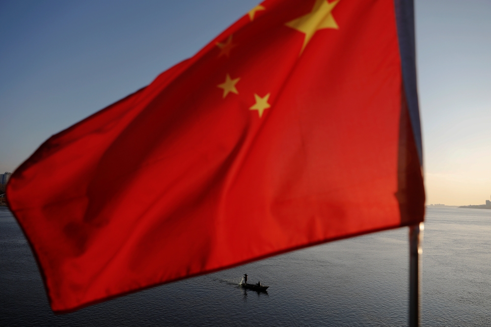 North Korean fishermen are seen as a Chinese flag flutters from the Broken Bridge as the sun sets over the Yalu River between the North Korean town of Sinuiju and Dandong in Liaoning Province, China, November 19, 2017. Reuters/Damir Sagolj