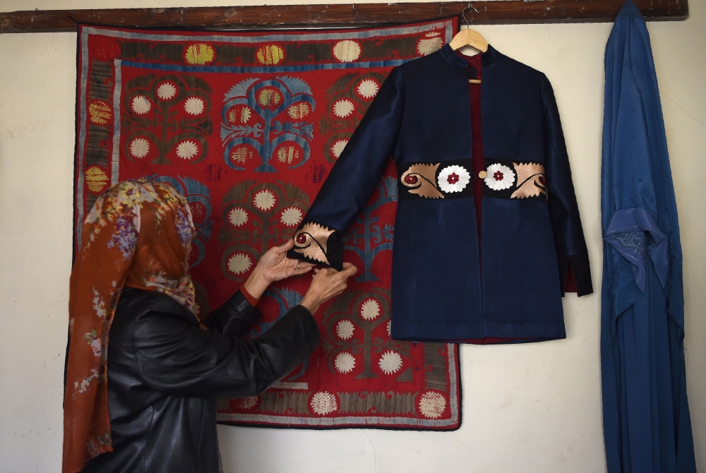 An Afghan tailor hanging an embroidered coat on the wall at Zarif Design House in Kabul. AFP / WAKIL KOHSAR 
 