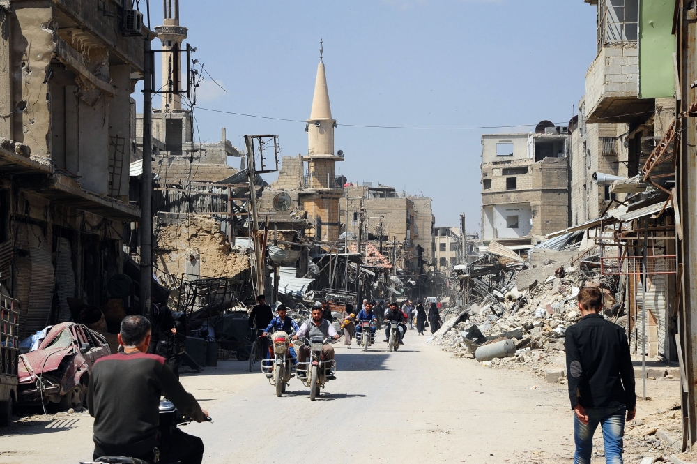 People walking down a street in the Eastern Ghouta town of Douma after Syrian government forces entered the last rebel bastion.  AFP / SANA 
