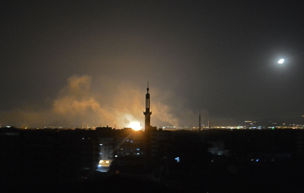 A general view shows smoke and flames rising from buildings in Yarmuk, a Palestinian refugee camp on the edge of Damascus, during overnight regime shelling on the southern district of the capital held by the Islamic State (IS) group on April 22, 2018.  AF