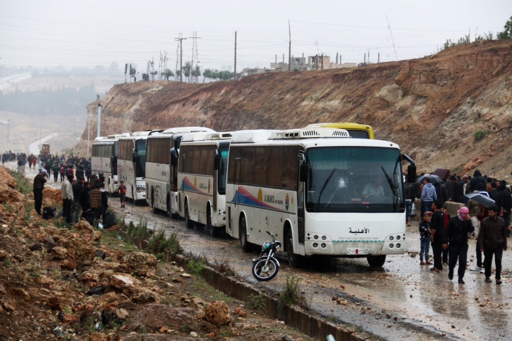 Syrians board buses prior to being evacuated from the rebel-held town of Rastan on May 7, 2018, after rebels and civilians were granted safe passage to the rebel-held town of Jarabulus, in Aleppo province, following a new deal between rebel fighters and t