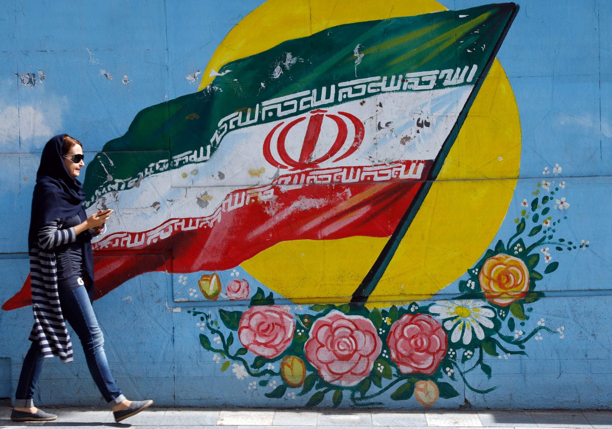 An Iranian woman walks past a mural of the Iranian flag in the capital Tehran on October 14, 2017. AFP