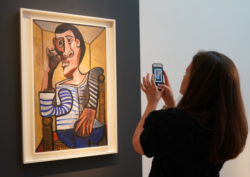 (FILES) In this file photo taken on May 3, 2018 a Christie's employee takes a picture of Pablo Picasso's 