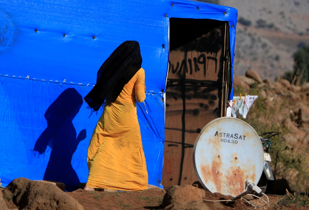 FILE PHOTO: A Syrian woman is seen near a tent in a refugee camp in Marjayoun, Lebanon November 16, 2017. REUTERS/Ali Hashisho