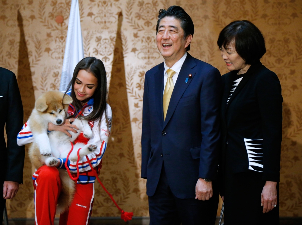 Russian figure skating gold medallist Alina Zagitova (L), Japanese Prime Minister Shinzo Abe (C) and his wife Akie Abe poses with an Akita Inu puppy presented to Zagitova in Moscow on May 26, 2018 during Abe's official visit to Russia. AFP / Alexander Zem