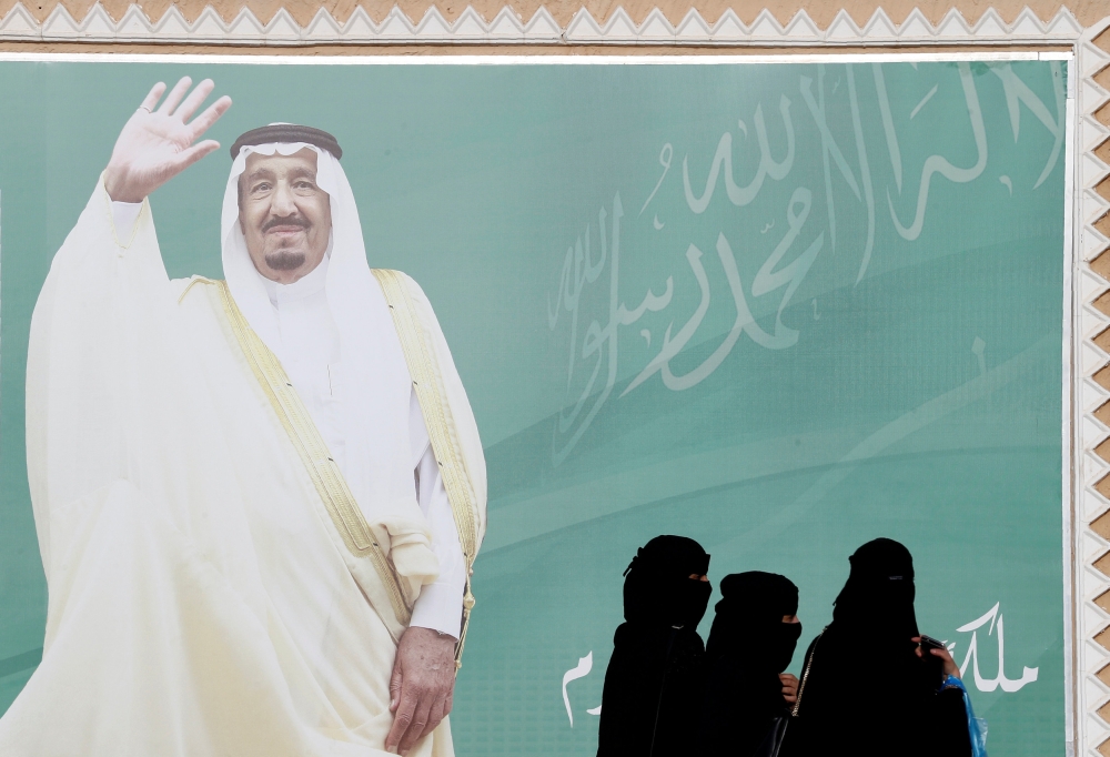 FILE PHOTO: Women walk past a poster of Saudi Arabia's King Salman bin Abdulaziz Al Saud during Janadriyah Cultural Festival on the outskirts of Riyadh, Saudi Arabia February 12, 2018. REUTERS/Faisal Al Nasser