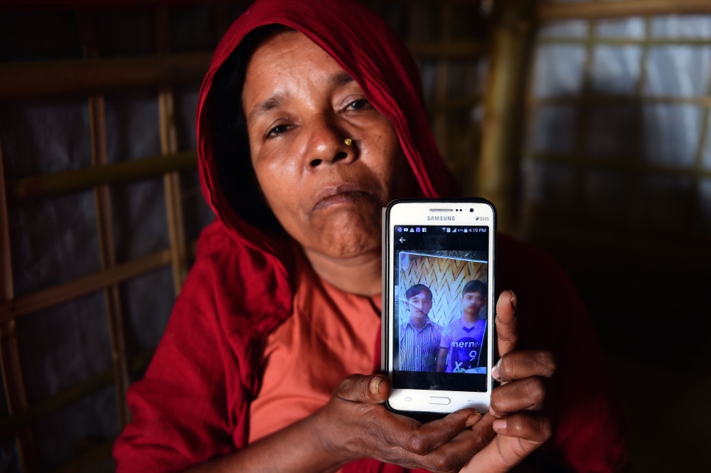 Rohingya Muslim refugee Khadija Begum, the mother of 16-year-old Rohingya youth Robi Alam, shows a photograph of two of her other sons during an interview with AFP at their house in Kutapalong refugee camp in Bangladesh's Cox's Bazar district. AFP / Munir