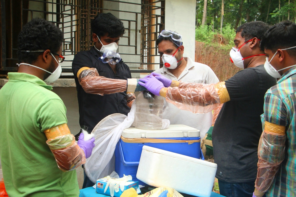 (FILES) In this file photo taken on May 21, 2018 Animal Husbandry department and Forest officials deposit a bat into a container after catching it inside a well at Changaroth in Kozhikode in the Indian state of Kerala. (AFP)