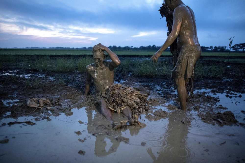 Devotees wearing costumes made of banana leaves cover themselves with mud as they prepare to head to church to attend a mass as part of a religious festival. AFP / NOEL CELIS