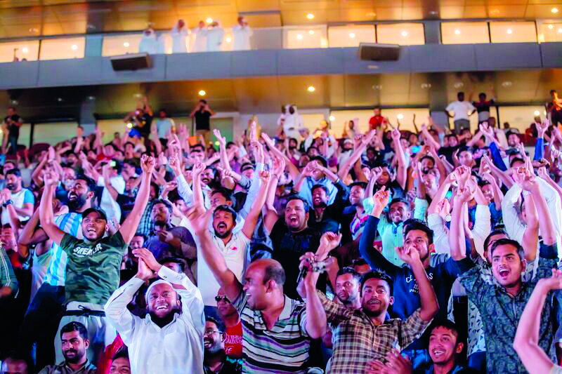 Football fans cheering at Khalifa International Stadium Fan Zone during a match. 