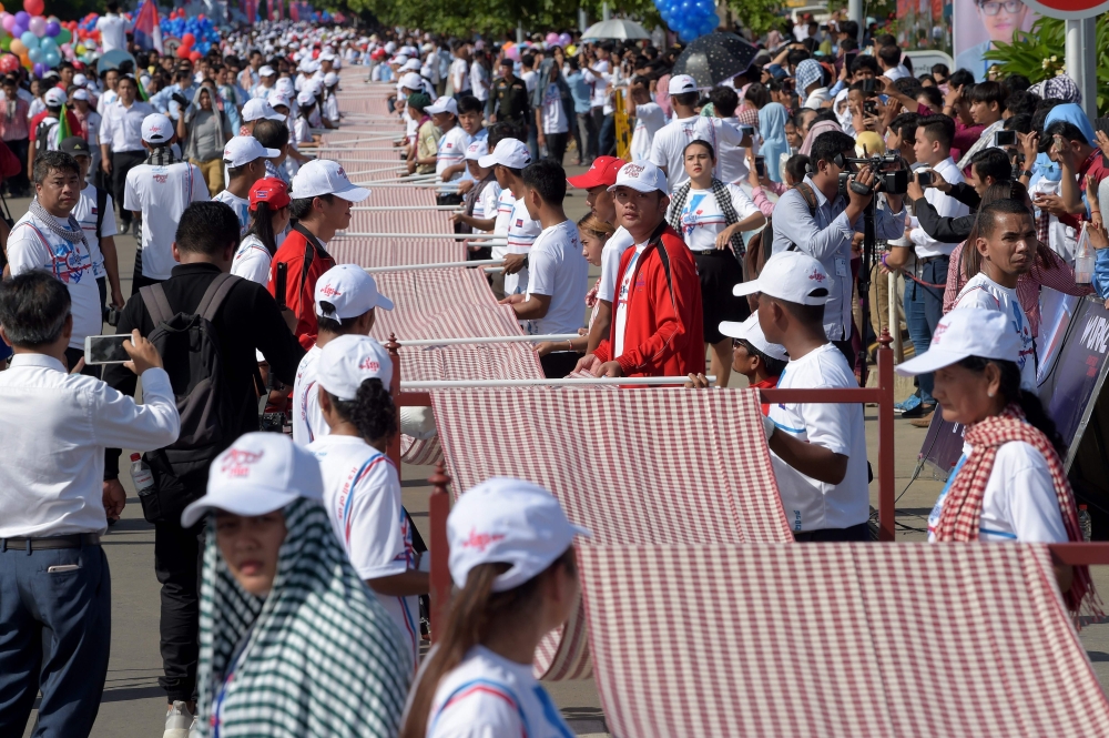 Cambodians roll out a 1,149.8 metre-long krama scarf so it can be declared as the world's longest hand woven scarf, in Phnom Penh on July 1, 2018. AFP / Tang Chhin Sothy

