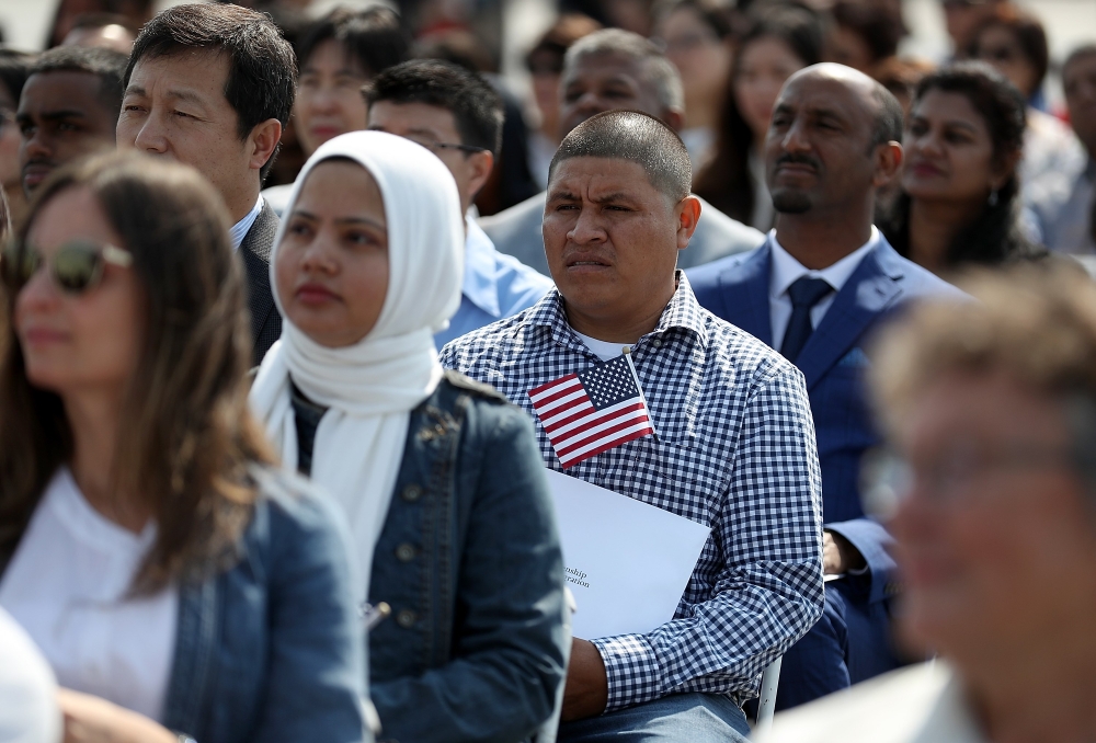 Immigrants look on before being sworn in as American citizens during a naturalization ceremony on the flight deck of the USS Hornet on July 3, 2018 in Alameda, California. 76 immigrants from 31 countries were sworn in as American citizens during a ceremon