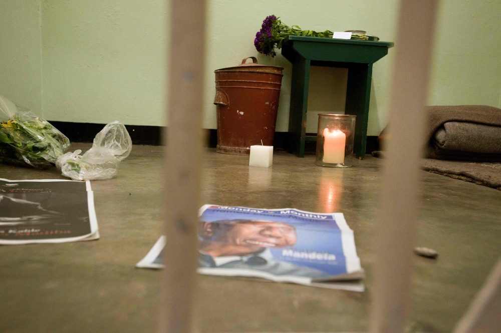 A candle burns in the former cell of Nelson Mandela during a visit of a group of activists, religious leaders and former prisoners (unseen) at Robben Island, Cape Town, for an all night vigil to commemorate Nelson Mandela, who was a prisoner on the island