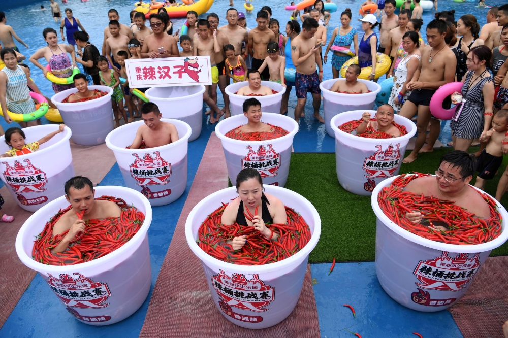 Participants take a bath in barrels filled with chilli peppers during the Spicy Barrel Challenge contest inside a water park in Chongqing, China July 7, 2018. Chen Chao/CNS via Reuters