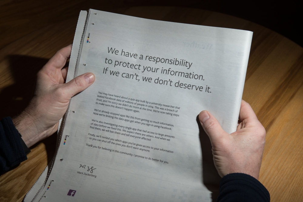 A man reads advertisement taken out by Mark Zuckerberg of Facebook to apologise for the leak of personal data on the backpage of a newspaper in Ripon, England on March 25, 2018. (AFP / Oli Scarff) 