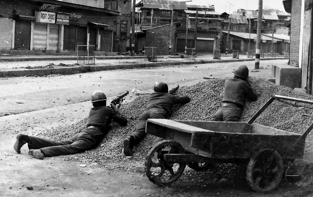 This photograph taken in 1989 shows Indian policemen taking positions after Kashmiri militants opened fire on government forces in the old city area of Naid Kadal in Srinagar.  AFP / Habib Naqash