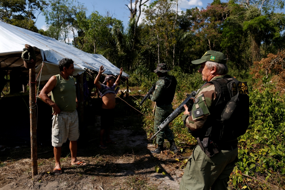  Agents of the Brazilian Institute for the Environment and Renewable Natural Resources, or Ibama, check a man at an illegal logging camp during 