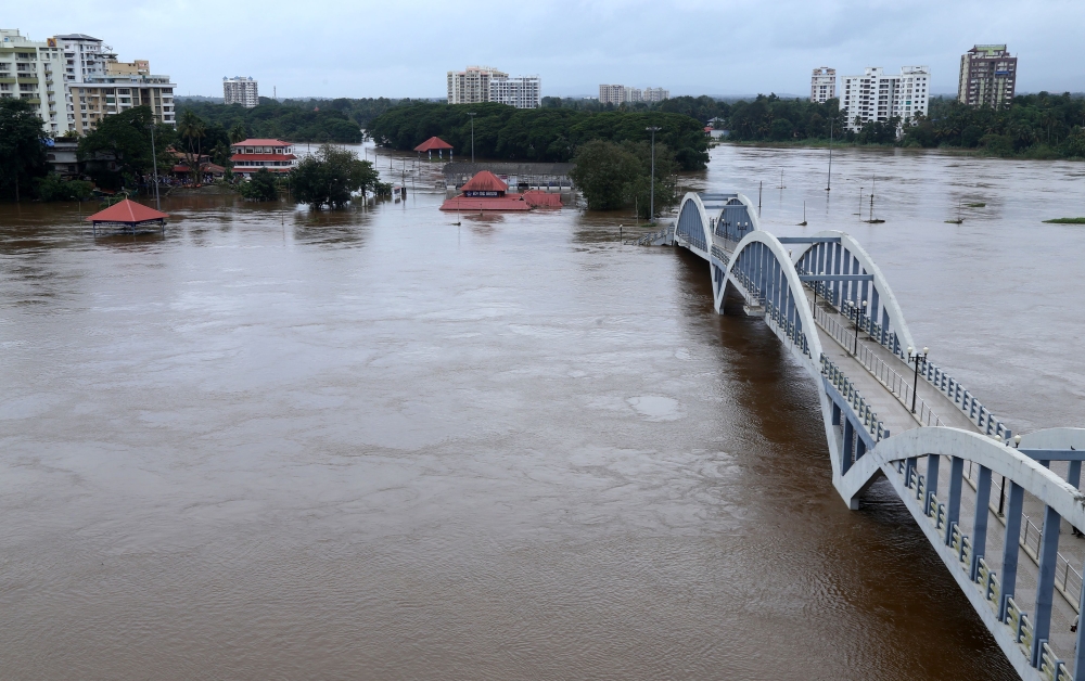 India residents stand on the shore as Periyar river flooded following monsoon rains at Aluva, in the Indian state of Kerala, on August 16, 2018. The death toll from floods in India's tourist hotspot of Kerala increased to 77 on August 16, as torrential ra