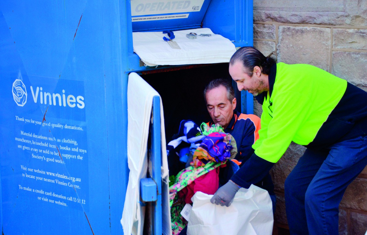 This photo taken on July 24, 2018 shows workers collecting clothing from a bin belonging to the St Vincent de Paul Society, a major charity recycling clothes, in Sydney. AFP / Peter Parks