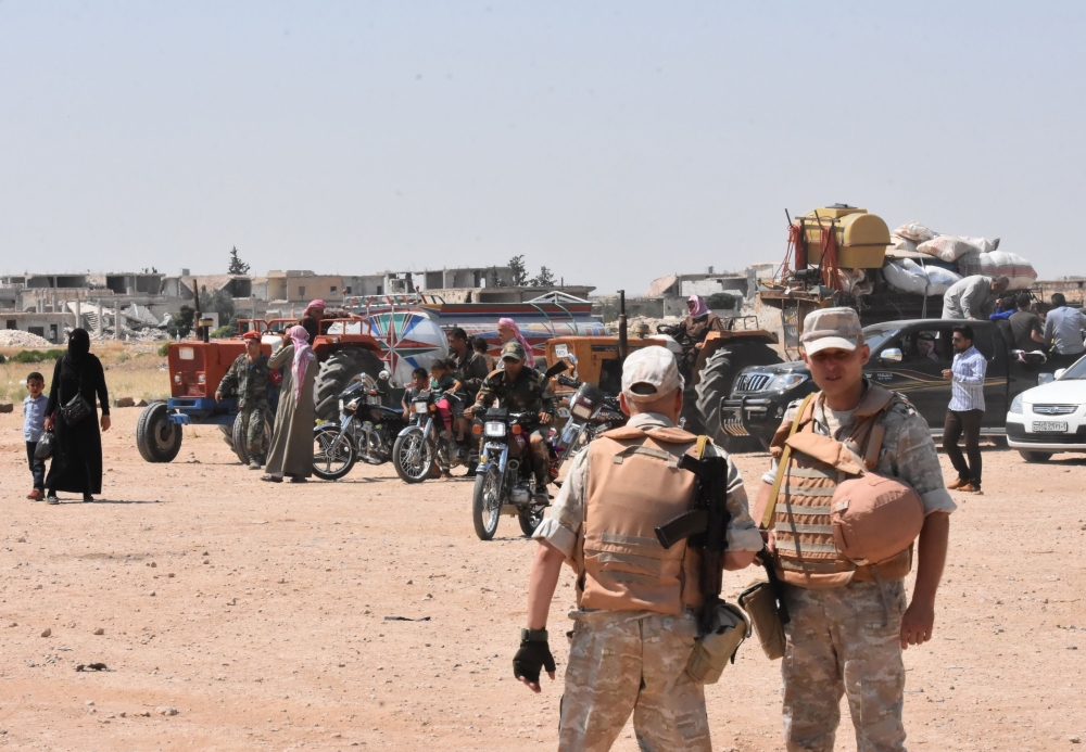 FILE PHOTO: Russian and Syrian forces stand guard as civilians enter the Abu Duhur crossing on the eastern edge of Idlib province on August 20, 2018. AFP / George OURFALIAN
