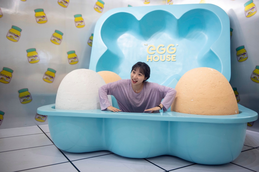 In this picture taken on August 31, 2018, a visitor poses for a photograph at the Egg House in Shanghai. / AFP / Johannes EISELE