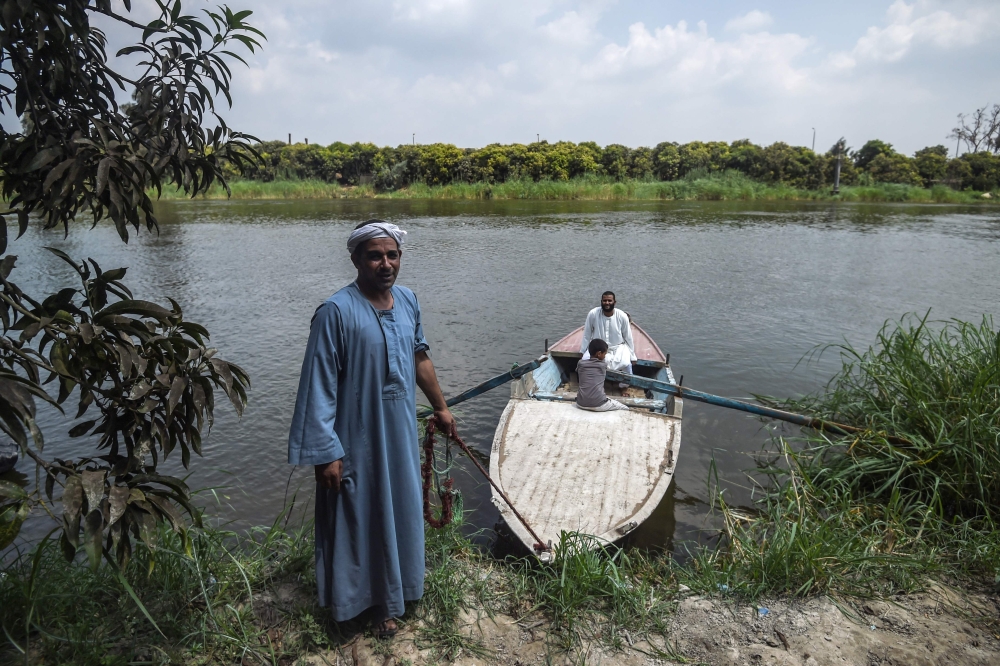 Workers in a mango farms ride a boat on a branch of the Nile, after finishing their work in the Al Qata village, Giza Governorate on August 27, 2018. / AFP / Mohamed el-Shahed 