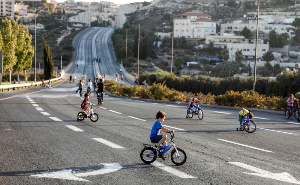 Palestinian youths ride bicycles along an empty street in east Jerusalem on September 19, 2018 as Jews mark Yom Kippur, the holiest day of the Jewish year, and abstain from driving.  AFP / Ahmad Gharabli
 