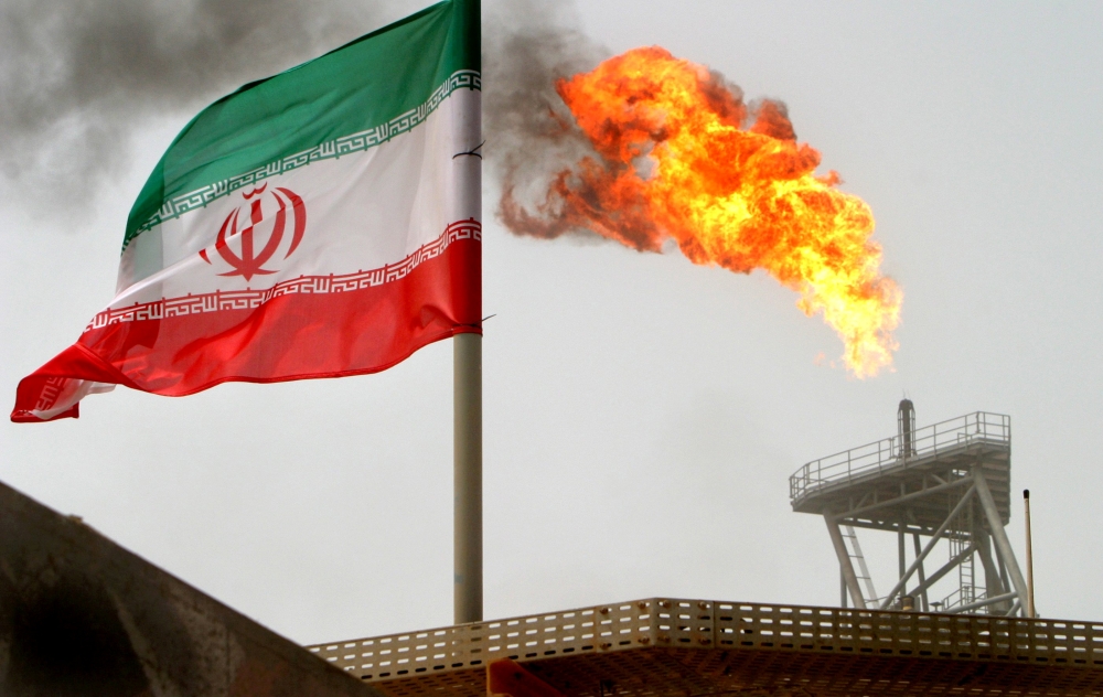 FILE PHOTO: A gas flare on an oil production platform in the Soroush oil fields is seen alongside an Iranian flag in the Persian Gulf, Iran, July 25, 2005. REUTERS/Raheb Homavandi