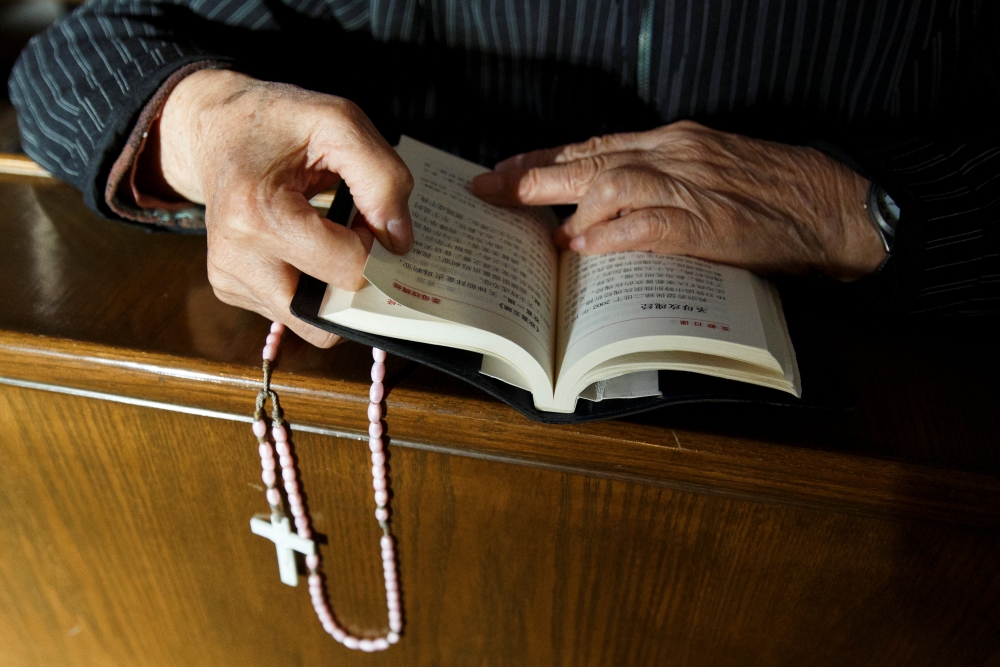 A believer reads the bible during mass at St. Joseph's Church, a government-sanctioned Catholic church, in Beijing, China, October 1, 2018. Reuters/Thomas Peter