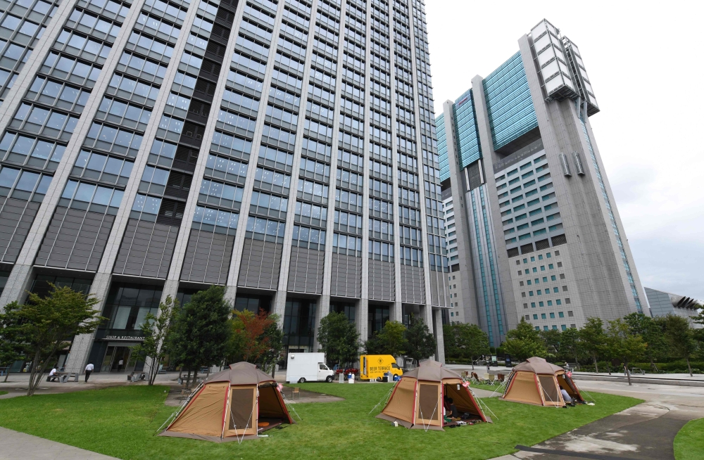 This photo taken on September 11, 2018 shows company employees working inside camping tents erected on the lawn outside an office building in Tokyo. AFP / Toshifumi Kitamura 