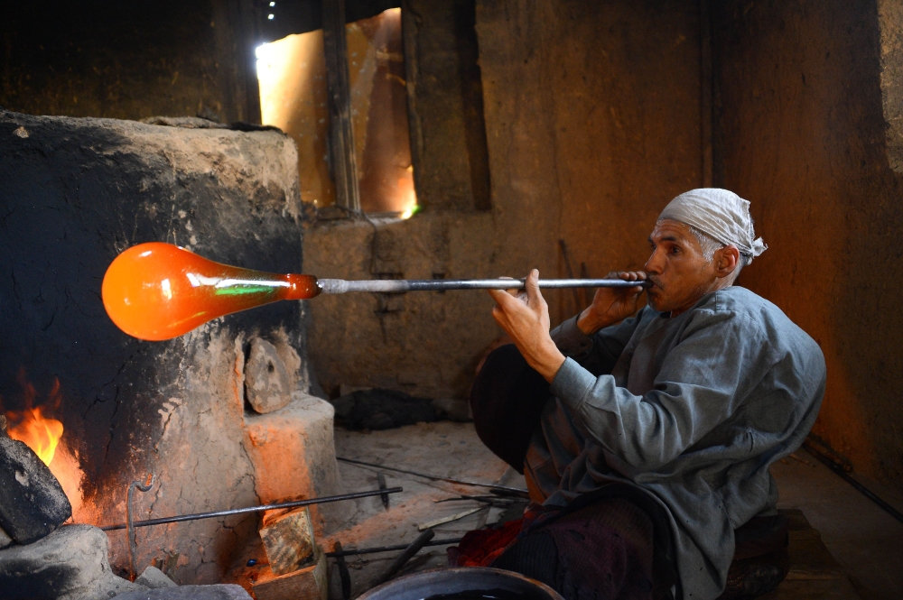 In this photo taken on August 2, 2018, Afghan man glassblower Ghulam Sakhi, mid-40s, crafts a glass object at his traditional glassblowing workshop in Herat province. AFP / HOSHANG HASHIMI 