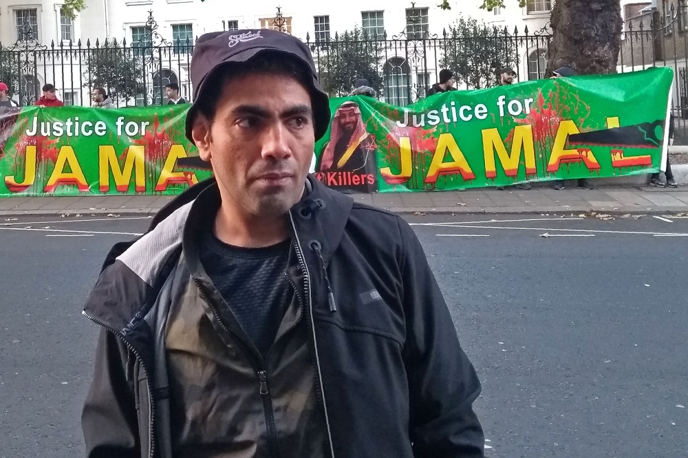 Saudi dissident satirist Ghanem Almasarir poses for a photograph in front of a protest outside the Saudi Arabian Embassy in west London on October 24, 2018, calling for justice for Jamal Khashoggi. AFP / Robin MILLARD