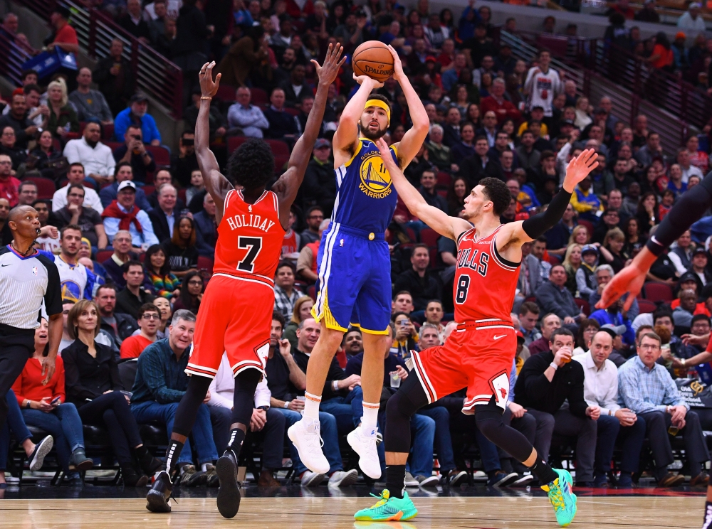 Golden State Warriors guard Klay Thompson (11) shoots the ball against Chicago Bulls forward Justin Holiday (7) and guard Zach LaVine (8) during the second half at the United Center. Mike DiNovo