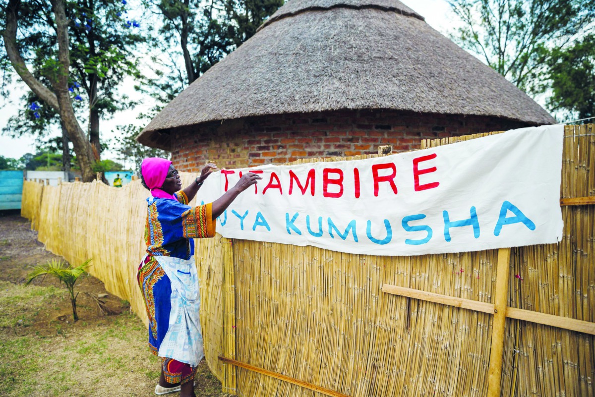 Poet, storyteller and retired schoolteacher, Hatifari Munongi adjusts a welcome banner reading at the replica traditional homestead she set up in the backyard of her house in the suburb of Marlborough in Harare on October 18, 2018.  AFP / Jekesai Njikizan